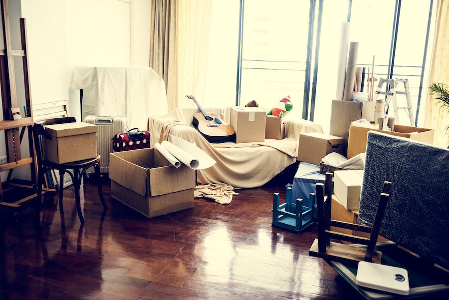 Partially-packed living space with open boxes, a guitar, and various household items.